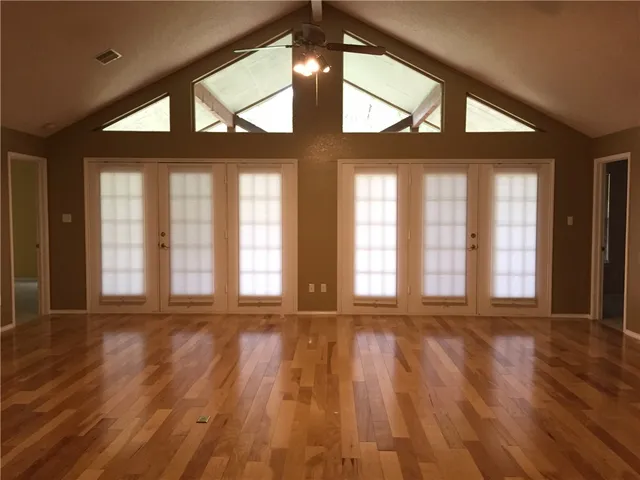 a view of an empty room with a large window and wooden floor