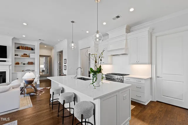 a kitchen with stainless steel appliances kitchen island granite countertop a table chairs and a refrigerator