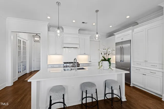 a kitchen with stainless steel appliances granite countertop a stove a sink refrigerator a dining table and chairs with wooden floor