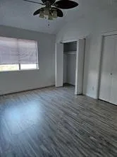 an empty room with wooden floor cabinet and windows