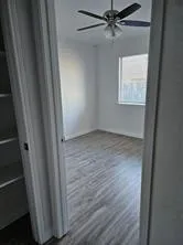 an empty room with wooden floor closet and windows