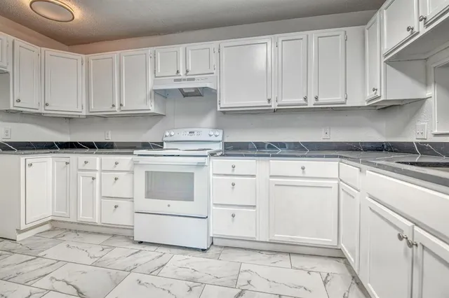a kitchen with granite countertop white cabinets and white appliances