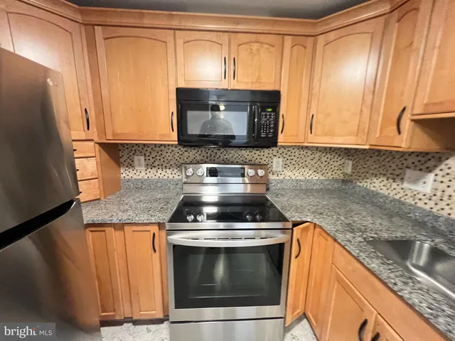 a kitchen with granite countertop a refrigerator stove and microwave