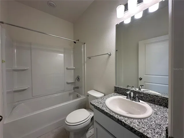 a bathroom with a granite countertop sink a mirror and a toilet