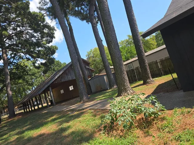 a backyard of a house with large trees and wooden fence