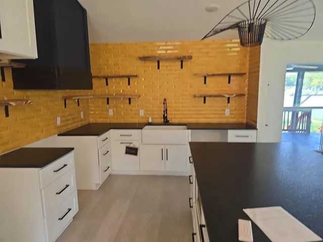 a kitchen with granite countertop a sink a stove and cabinets