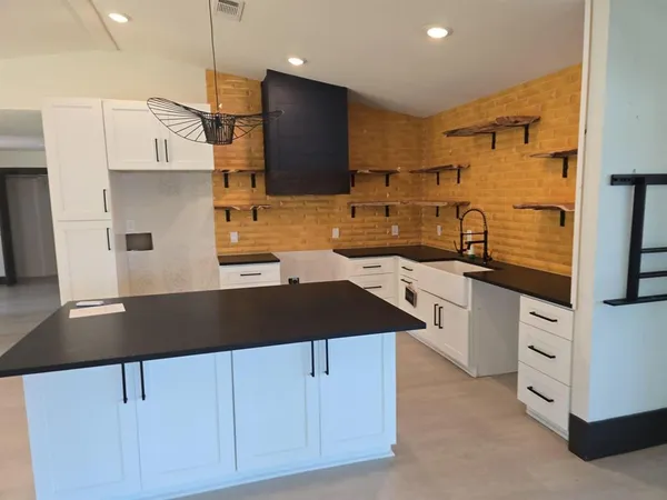 a kitchen with kitchen island granite countertop a sink a stove and a refrigerator