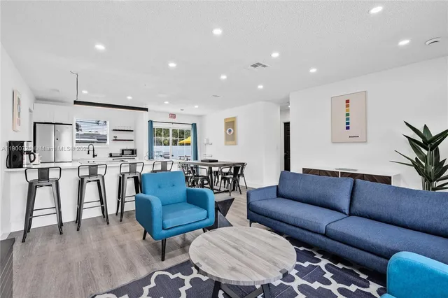 a living room kitchen with furniture and a dining table with wooden floor