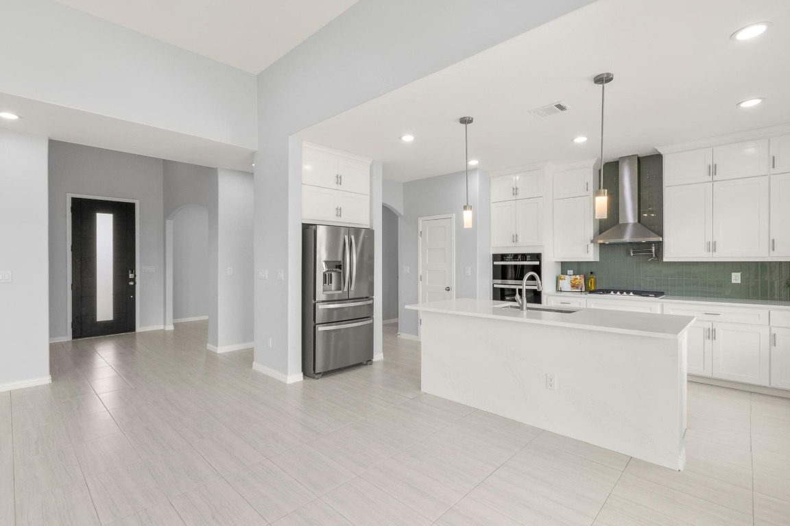 1136 County Road 484 Elgin, TX 78621 - Photo 11 of 37 Kitchen featuring stainless steel fridge with ice dispenser, wall chimney exhaust hood, arched walkways, light countertops, and recessed lighting