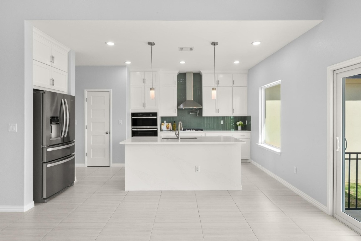 1136 County Road 484 Elgin, TX 78621 - Photo 10 of 37 Kitchen featuring stainless steel fridge, wall chimney range hood, light countertops, plenty of natural light, and recessed lighting
