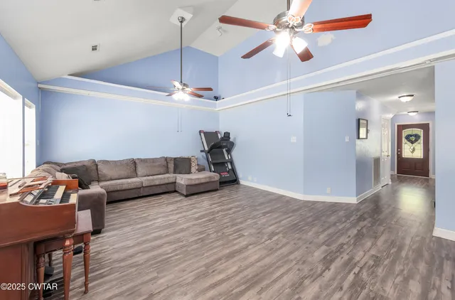 a living room with furniture and a chandelier fan