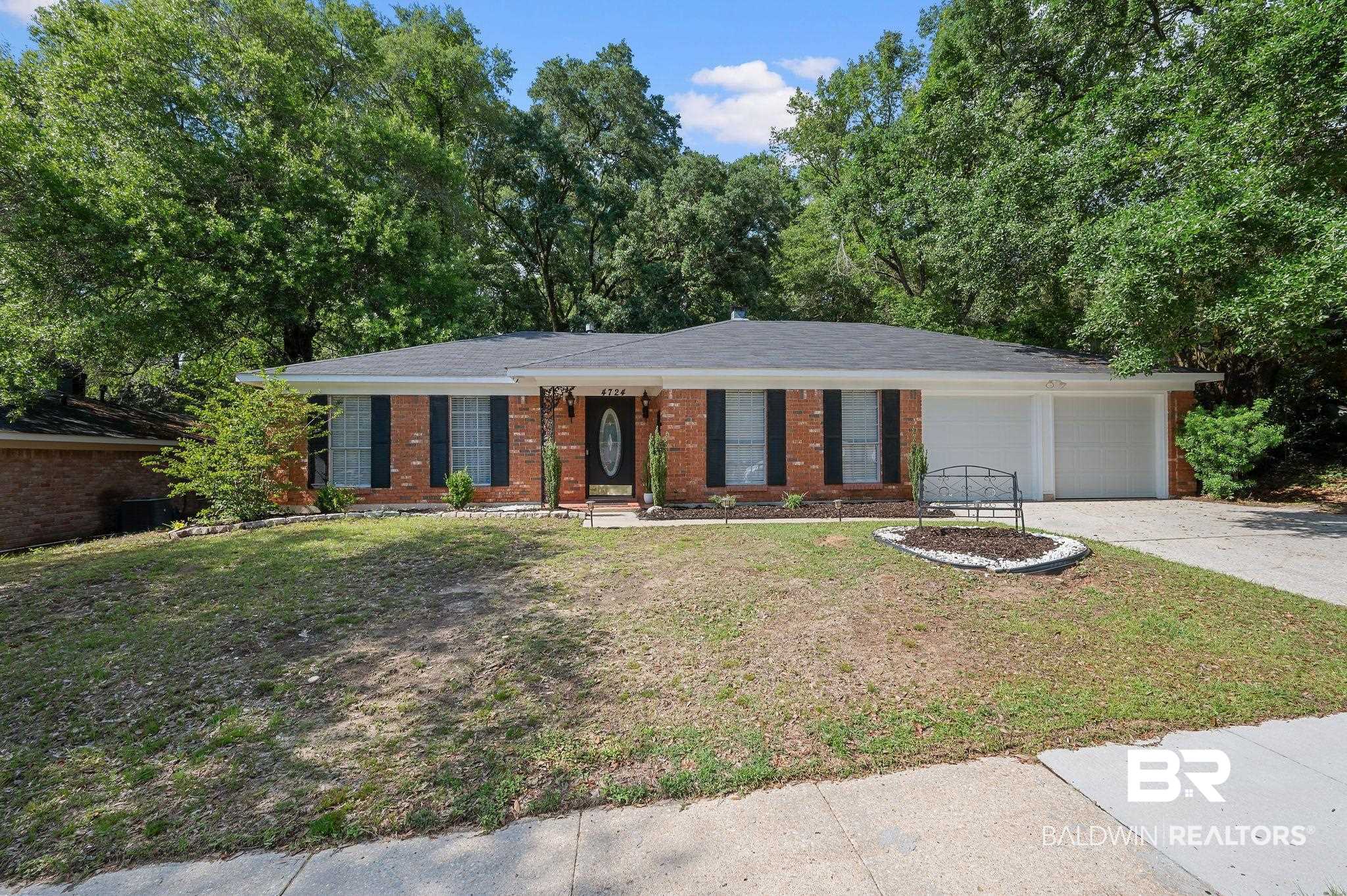 4724 Wicker Way Mobile, AL 36609 - Photo 1 of 36 Brick facade residence featuring a dark shingle roof, a two-car garage with white doors, and a front entry with a dark door and decorative glass insert