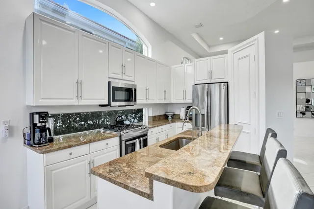 a kitchen with granite countertop a sink a stove and refrigerator