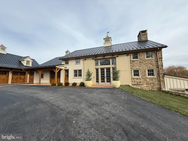front view of house with a yard and trees all around