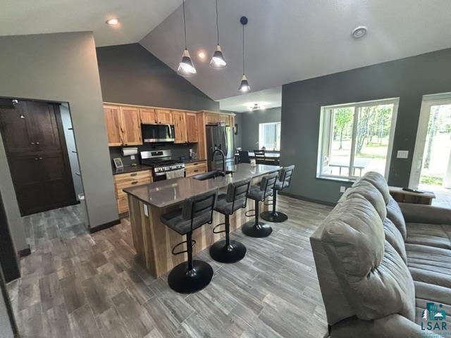 3454 Anderson Road Hibbing, MN 55746 - Photo 5 of 31 Open-concept kitchen featuring wood-finish cabinetry, stainless steel appliances, a center island with bar seating, and wood-look tile flooring
