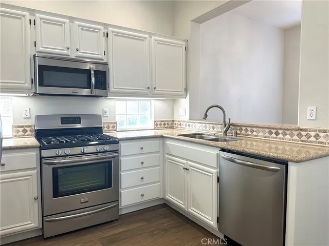a kitchen with stainless steel appliances granite countertop a stove microwave and sink