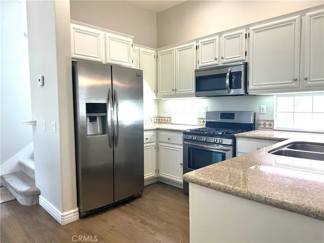 a kitchen with stainless steel appliances granite countertop a refrigerator a stove top oven a sink and dishwasher