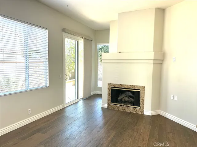 an empty room with wooden floor fireplace and windows