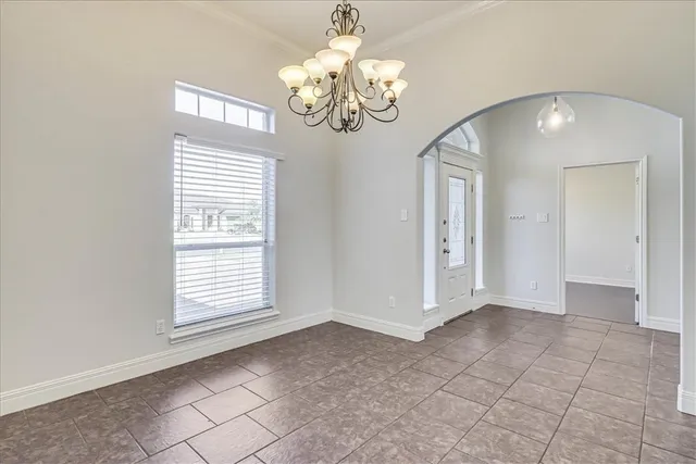 an empty room with chandelier and windows