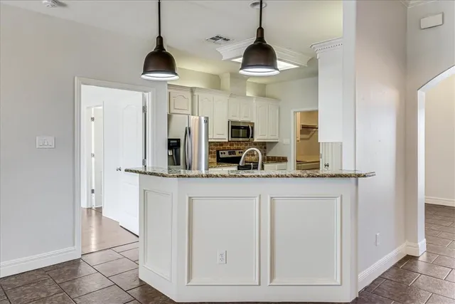 a kitchen with stainless steel appliances granite countertop a sink a stove and a refrigerator