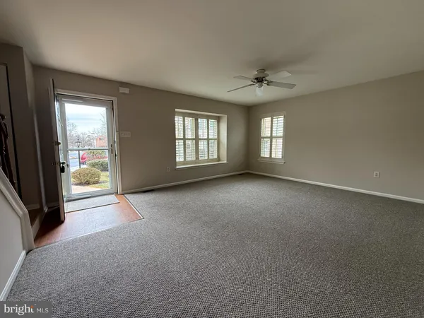 an empty room with windows and ceiling fan