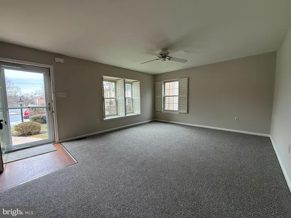an empty room with windows and ceiling fan
