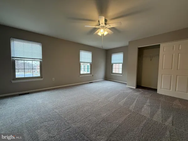 an empty room with windows and fan chandelier