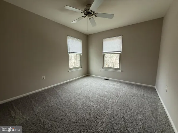 an empty room with windows and chandelier fan