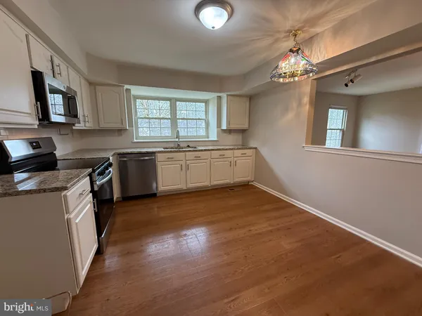 a large kitchen with cabinets wooden floor and stainless steel appliances