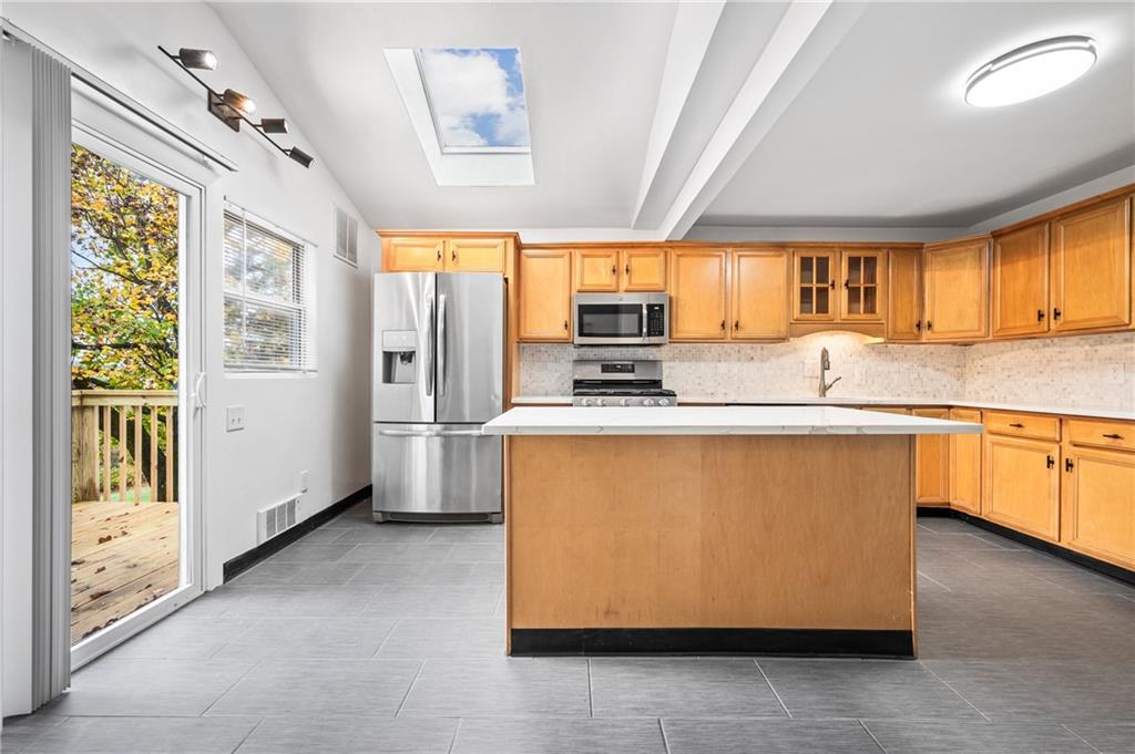 63 Herbst Road Coraopolis, PA 15108 - Photo 8 of 19 a kitchen with stainless steel appliances granite countertop a refrigerator a sink dishwasher a stove a dining table and chairs with wooden floor