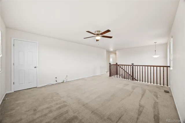an empty room with wooden floor cabinet and windows