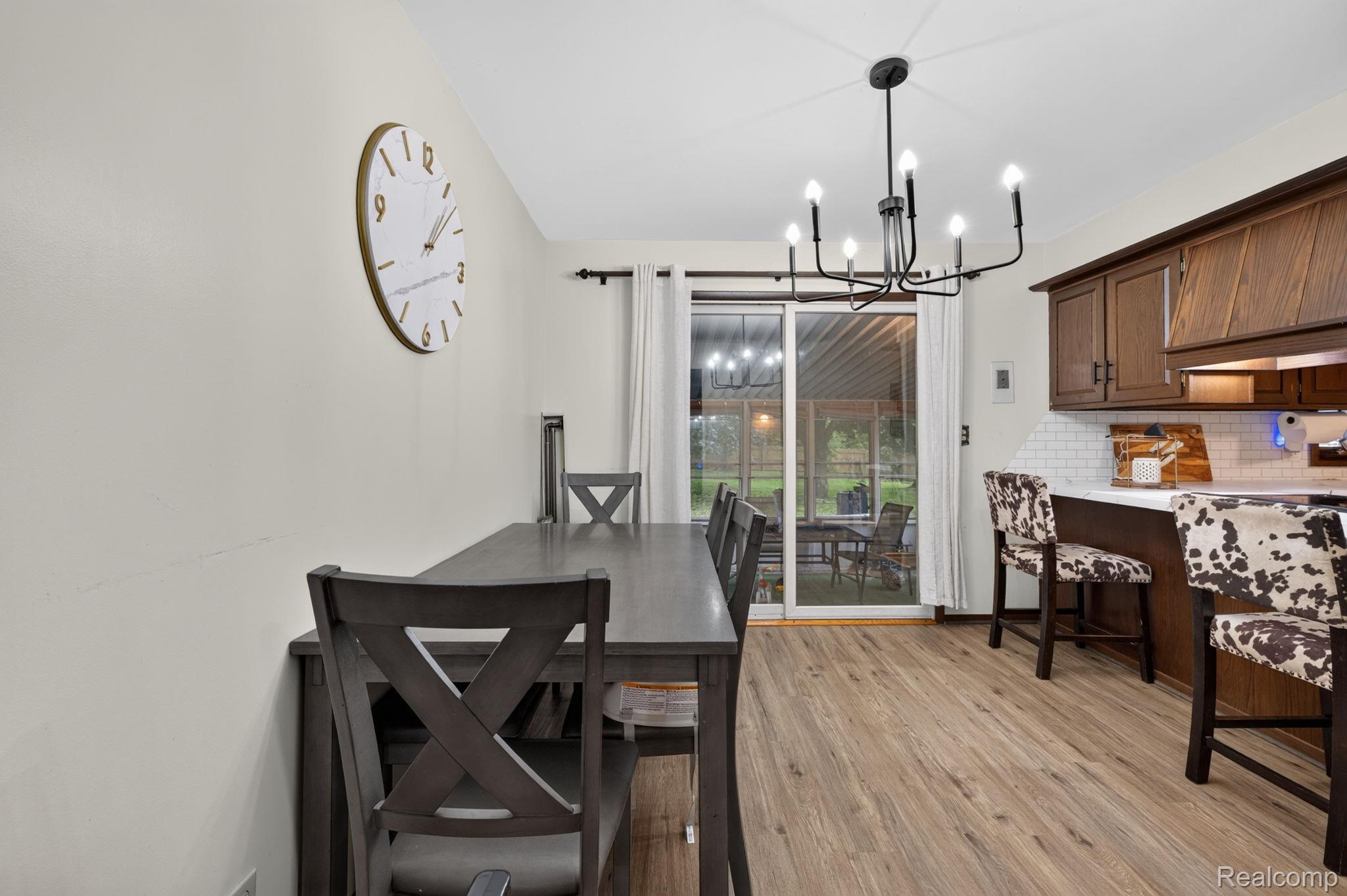 5330 Sheridan Road Saginaw, MI 48601 - Photo 16 of 50 Dining area featuring wood-finish flooring, a contemporary chandelier, and a sliding glass door providing access to an outdoor area