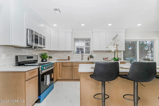 a kitchen with stainless steel appliances granite countertop a table chairs sink and cabinets