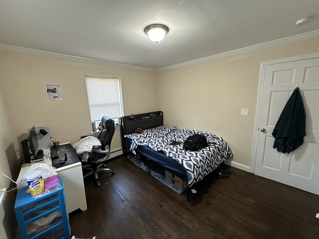 435 Walnut Avenue, Unit A Boston, MA 02119 - Photo 4 of 12 a bedroom with a bed and wooden floor