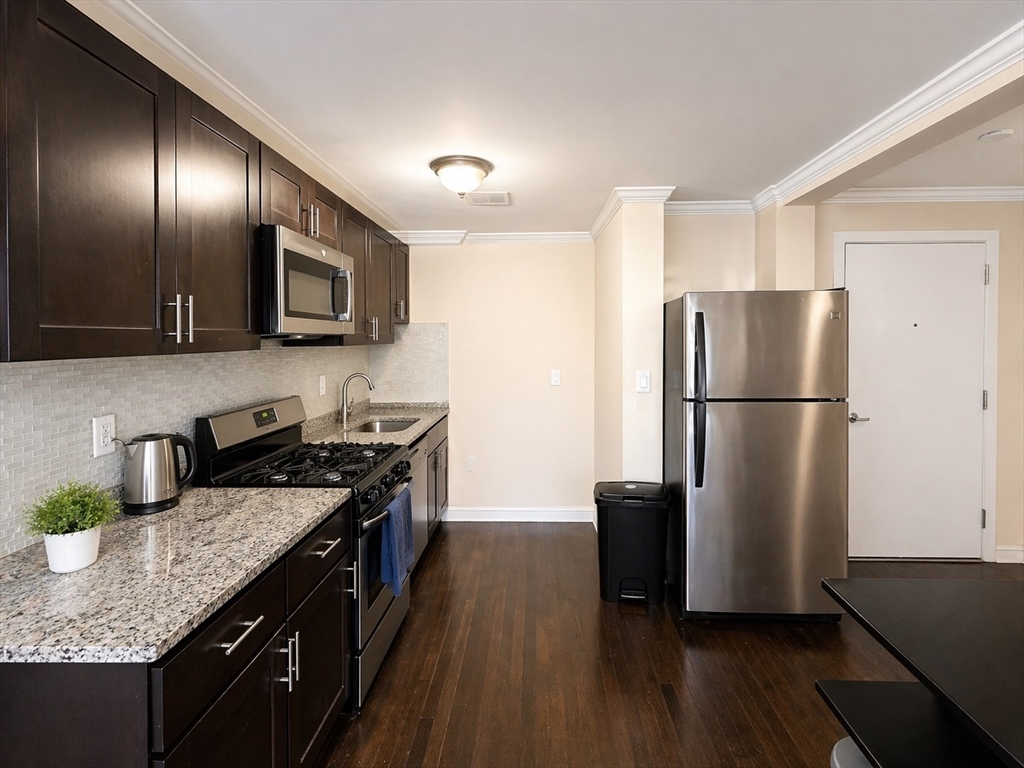 435 Walnut Avenue, Unit A Boston, MA 02119 - Photo 6 of 12 a kitchen with granite countertop stainless steel appliances a refrigerator microwave and sink