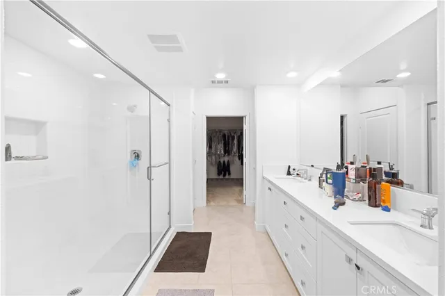 a large bathroom with a double vanity sink a large mirror and shower