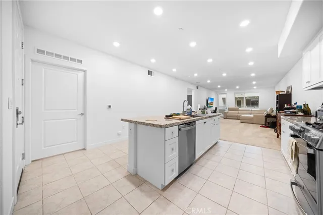 a kitchen with stainless steel appliances kitchen island granite countertop a refrigerator and a sink