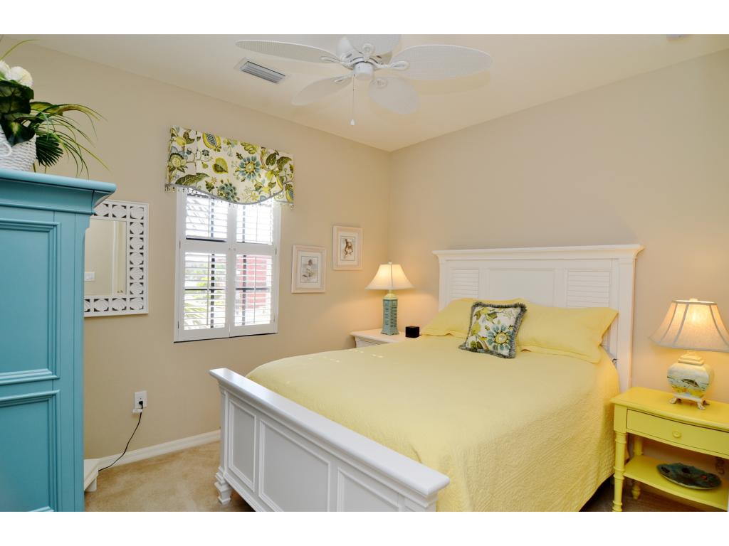 8997 Cambria Circle, Unit 2002 Naples, FL 34113 - Photo 11 of 18 a bedroom with a bed and a chandelier