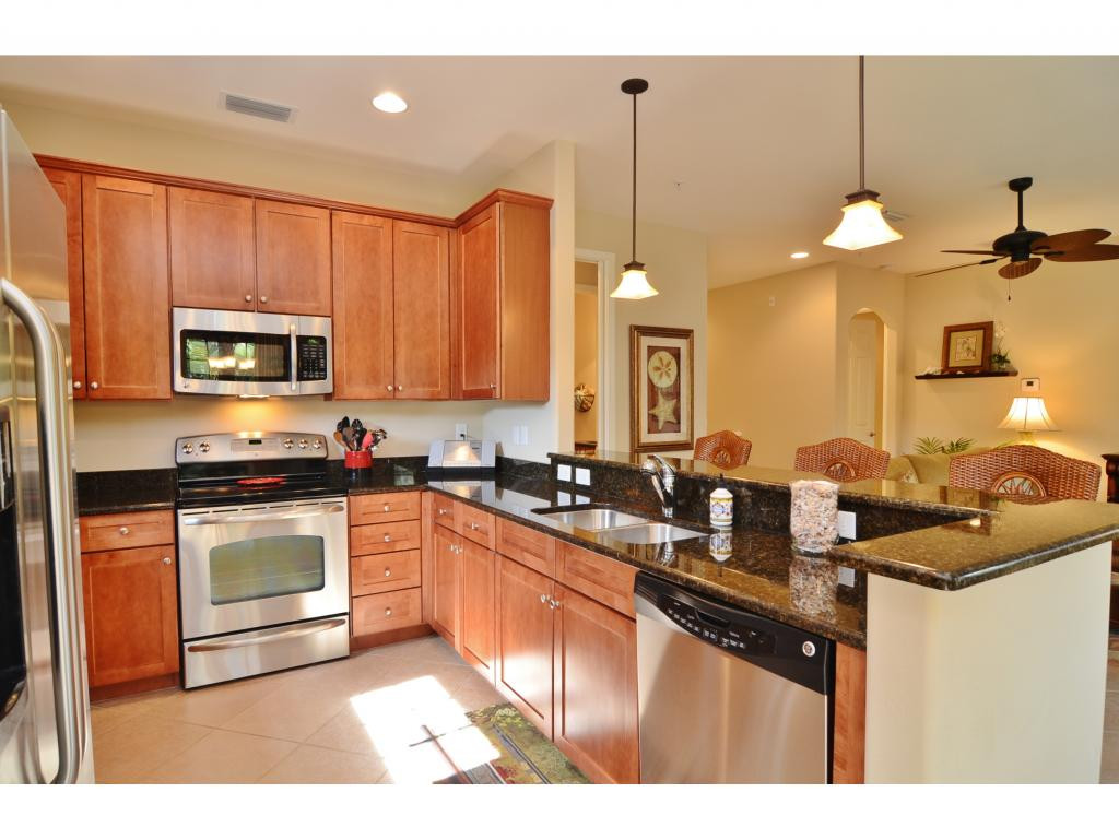 8997 Cambria Circle, Unit 2002 Naples, FL 34113 - Photo 5 of 18 a kitchen with stainless steel appliances granite countertop a sink a stove and a microwave