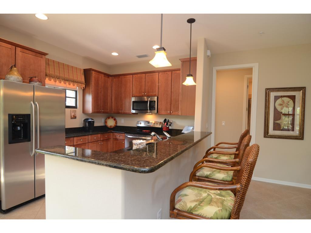 8997 Cambria Circle, Unit 2002 Naples, FL 34113 - Photo 6 of 18 a kitchen with stainless steel appliances granite countertop a sink refrigerator and cabinets