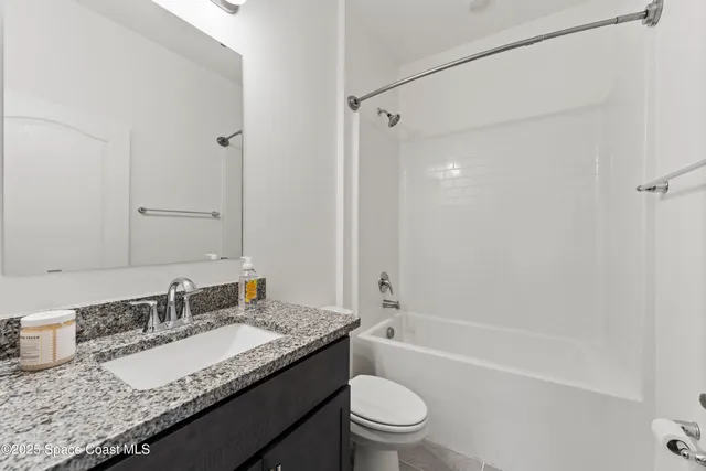 a bathroom with a granite countertop sink a toilet and shower