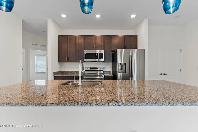 a kitchen with stainless steel appliances granite countertop a sink refrigerator and microwave