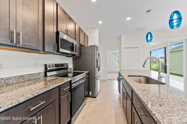 a kitchen with granite countertop stainless steel appliances a sink stove and refrigerator