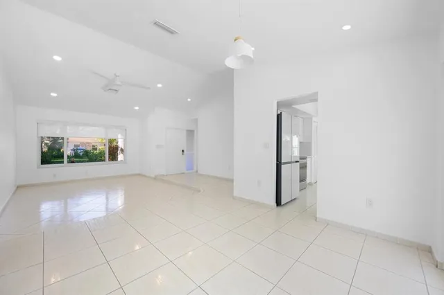 an empty room with kitchen and natural light
