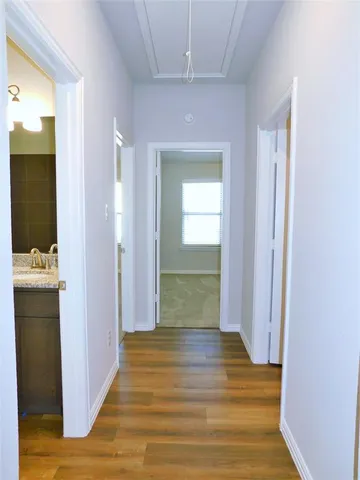 a view of a hallway with wooden floor and a bathroom