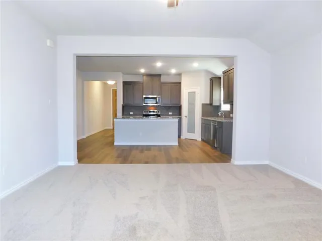 a view of a kitchen with kitchen island a sink wooden floor and a refrigerator