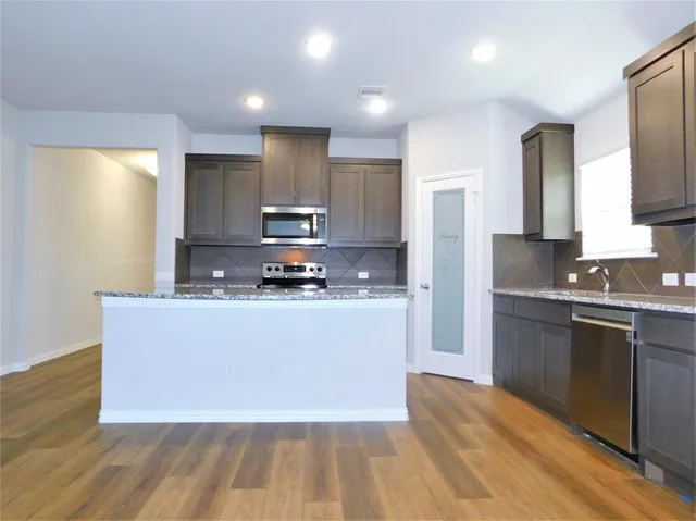 a kitchen with stainless steel appliances granite countertop a stove a sink and a refrigerator
