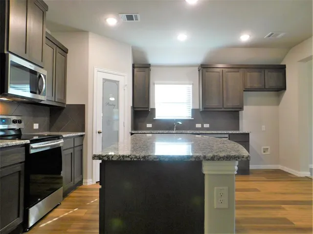a kitchen with stainless steel appliances granite countertop a stove a sink and a microwave