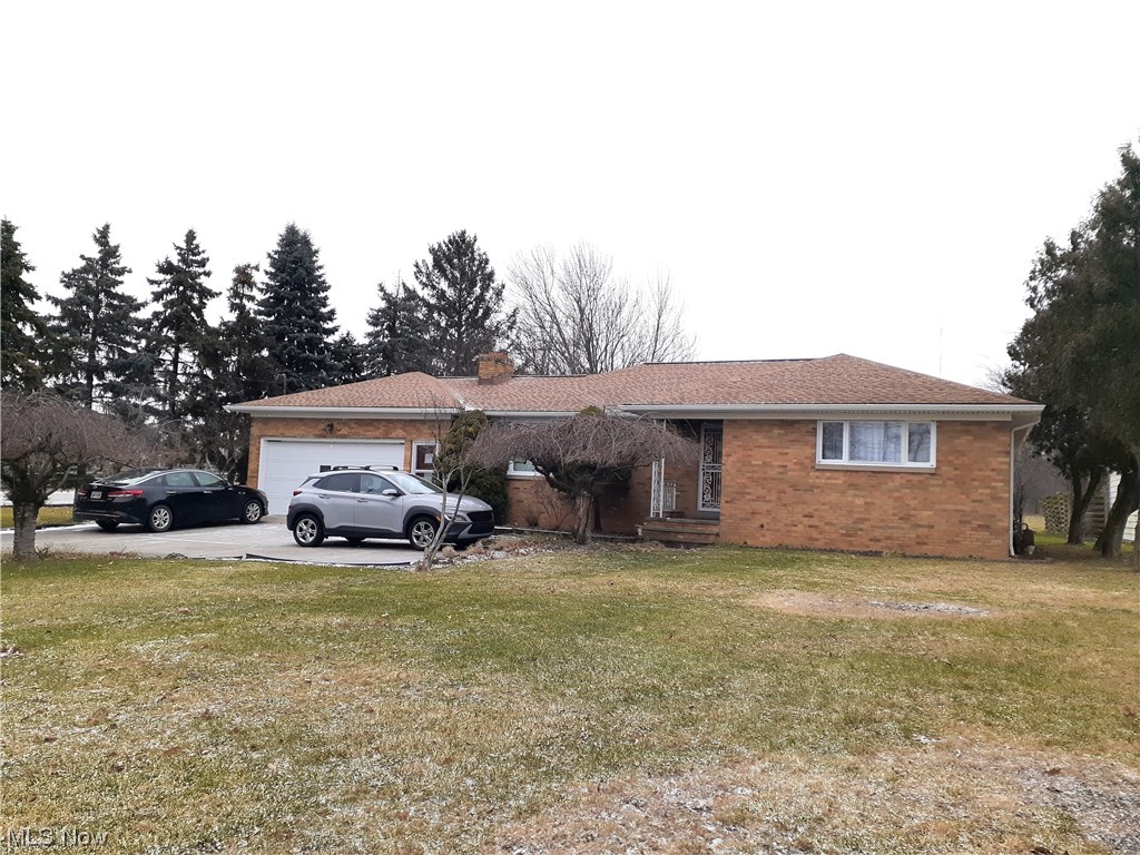 Ranch-style house featuring a garage and a front yard