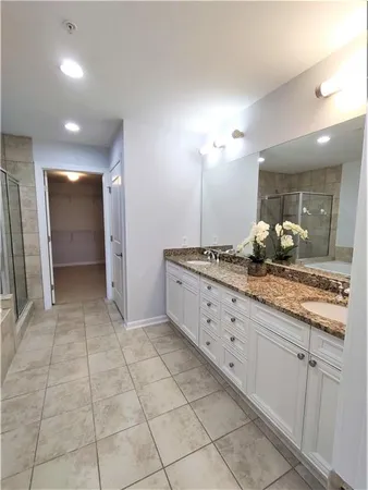 a bathroom with a granite countertop sink a mirror and a shower